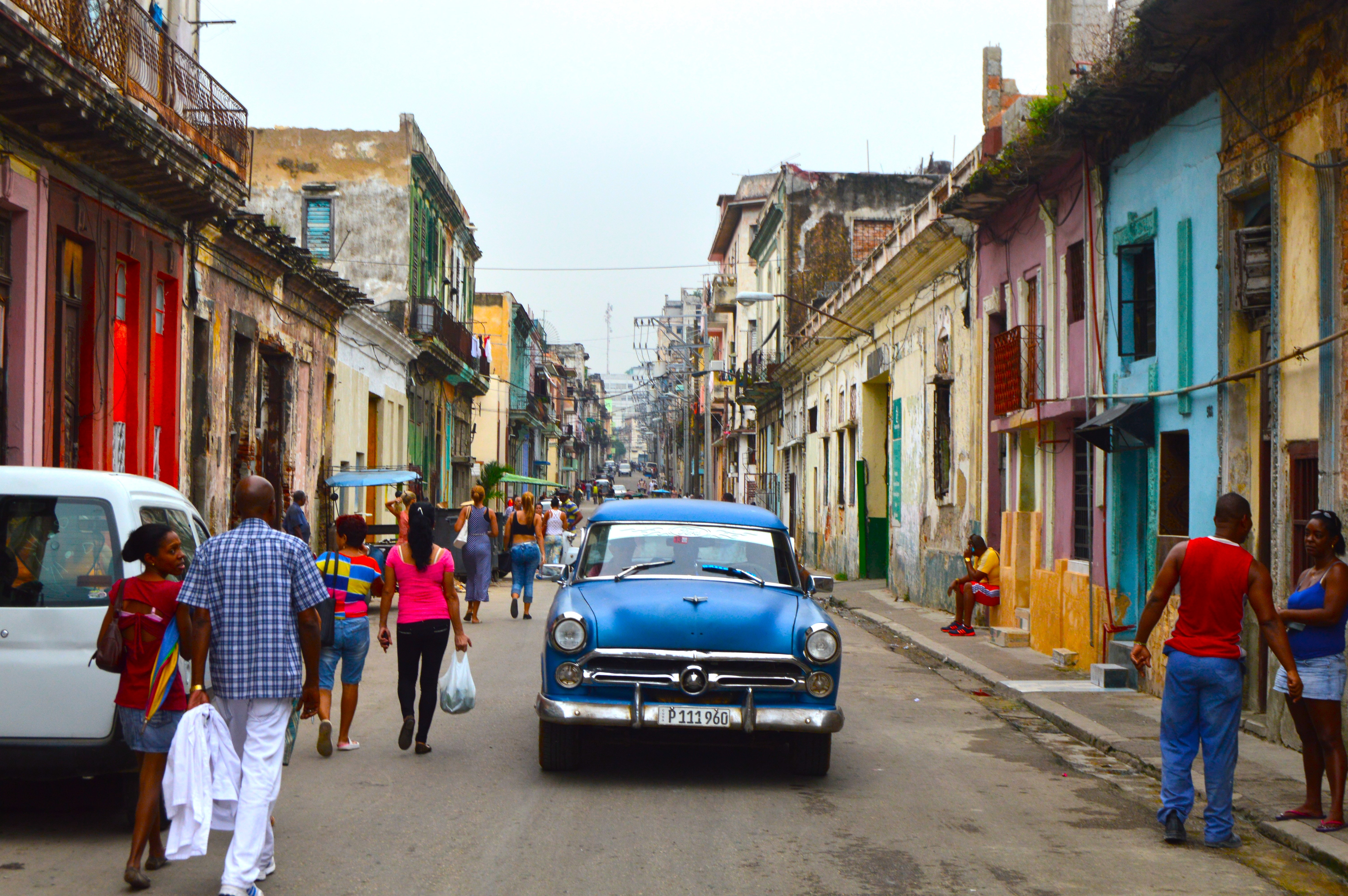 Calle concurrida de La Habana: autos clásicos de los años 70 y transeúntes a los lados